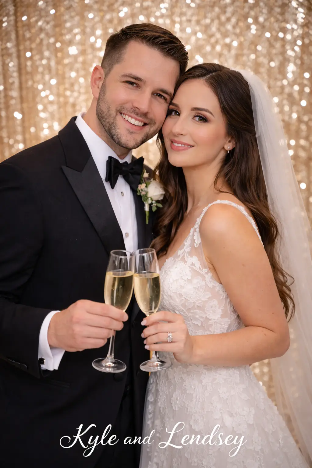 Bride and groom smiling while holding champagne glasses in front of a gold sequin backdrop at their wedding reception.